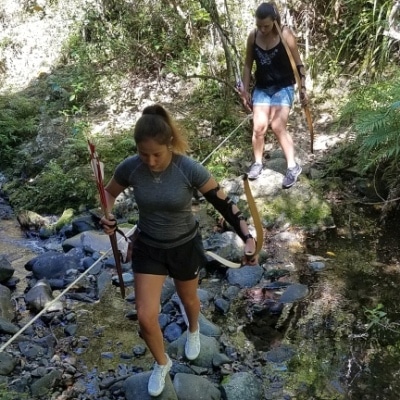 People with bow and arrow crossing a stream at Archery Park Nelson